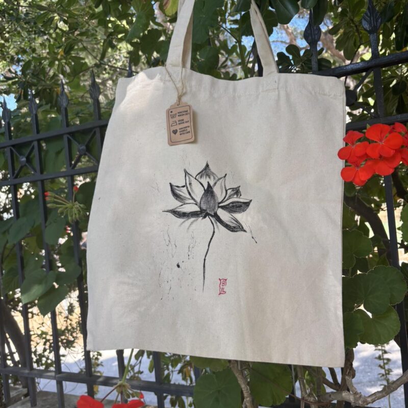 Hand-painted beige canvas tote bag featuring a minimalist black lotus flower with expressive brushstrokes.